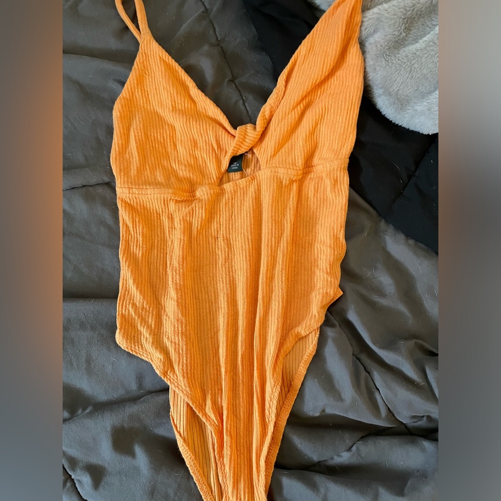 yellowish orange body suit with open cross in middle